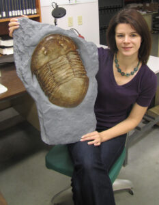 Photograph of Brenda Hunda with a trilobite fossil.